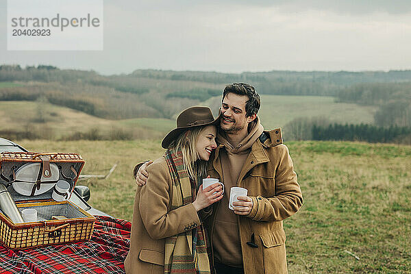 Loving couple holding tea cups and embracing each other