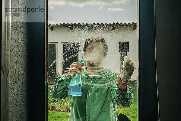 Man cleaning window with soap solution