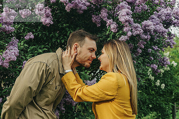 Happy couple embracing each other under lilac flower tree