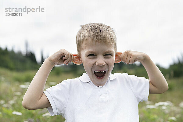 Playful boy making funny face in meadow