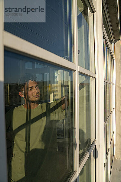 Young man seen through window on sunny day