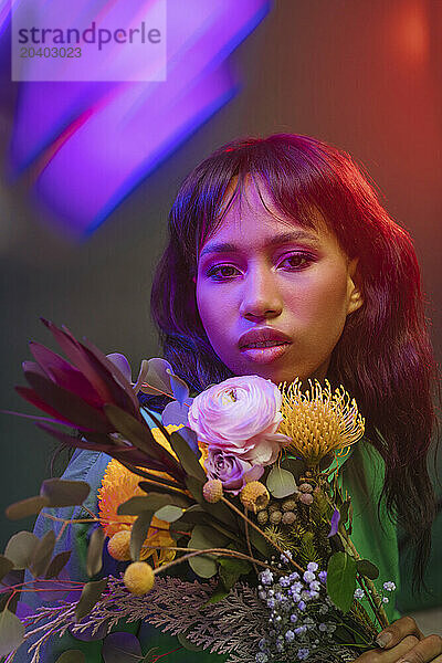 Young woman with colorful flowers and neon lights