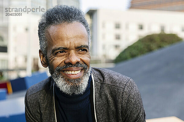 Happy mature businessman in front of buildings on street