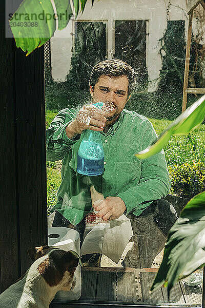 Man spraying liquid soap on glass window