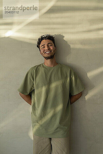 Happy young man leaning on wall