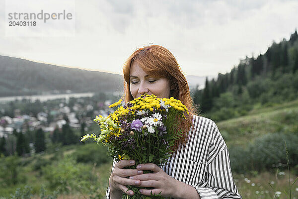 Redhead woman smelling bouquet of wild flowers