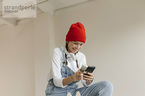 Smiling woman using smart phone in new home