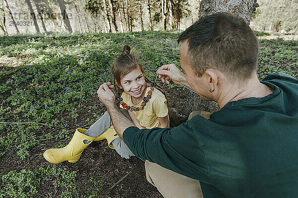 Father and daughter with natural necklace in forest