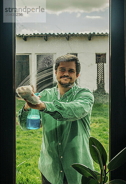 Man wiping window with paper napkin