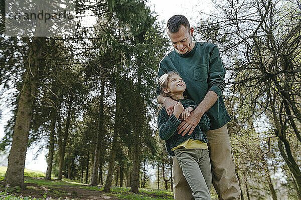 Father playing with daughter in forest