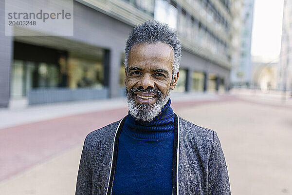 Happy businessman in front of buildings at office park