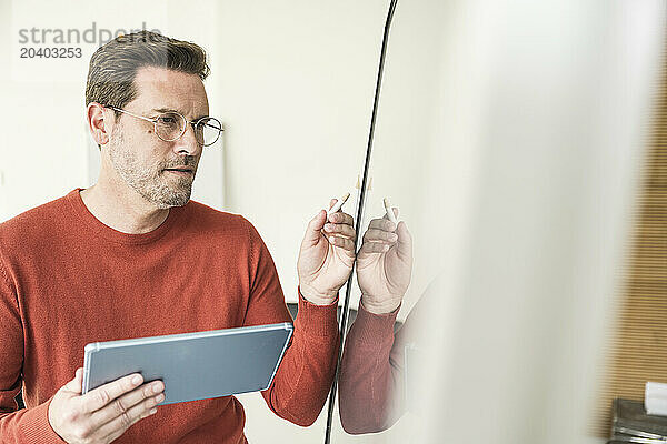 Confident mature businessman with tablet PC using touch screen in office