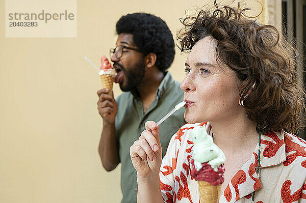 Friends eating ice cream in front of wall