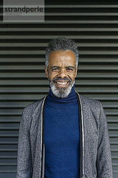 Smiling mature businessman standing in front of shutter