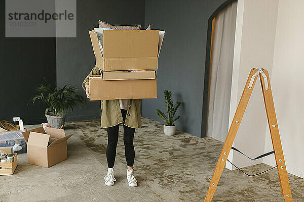 Woman carrying cardboard boxes standing in new home