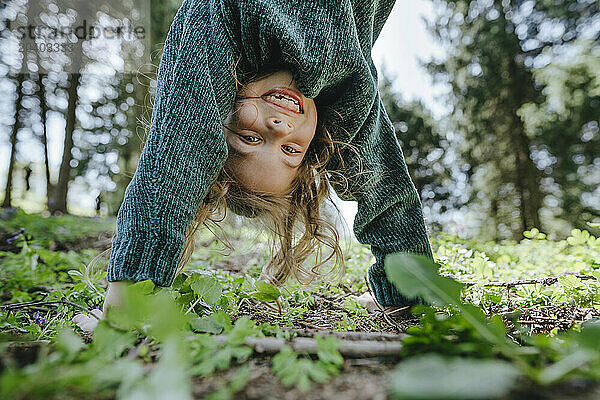 Smiling girl doing handstand in forest