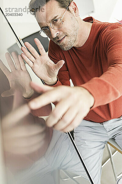 Confident mature businessman touching screen in office