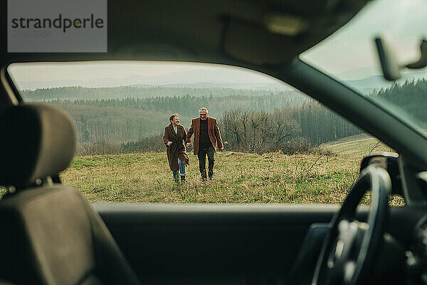 Happy senior couple enjoying vacations on mountain seen through car window