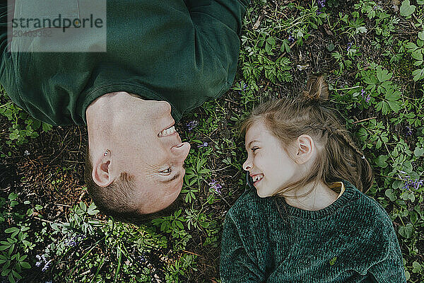 Smiling girl with father lying on grass in forest