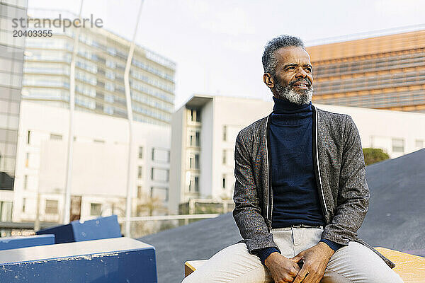 Mature businessman sitting on table near buildings