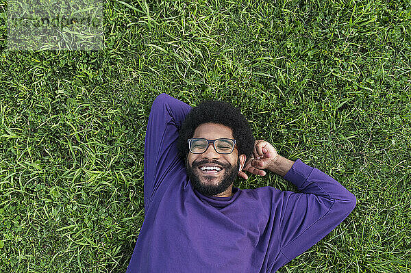 Smiling man lying on green grass in lawn