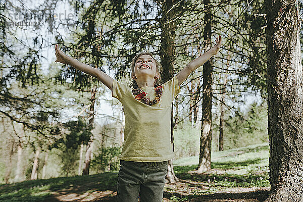 Happy girl with arms outstretched standing in forest