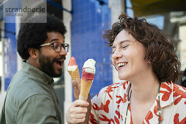 Happy couple eating ice cream cones in front of building