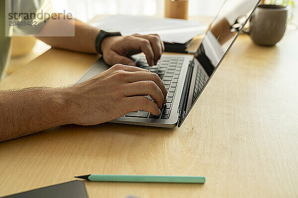 Hands of freelancer typing on laptop at home