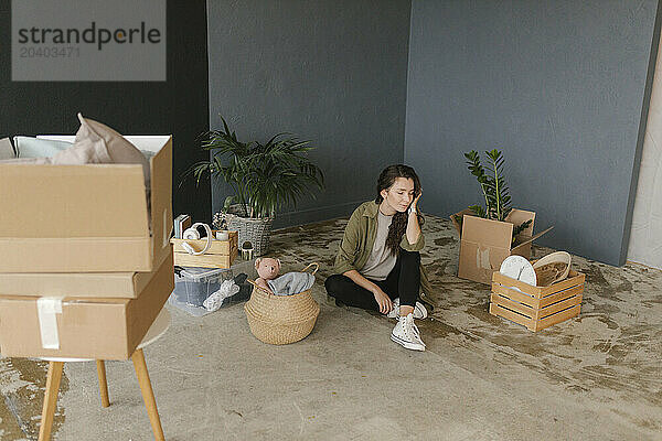 Woman sitting amidst boxes in new home