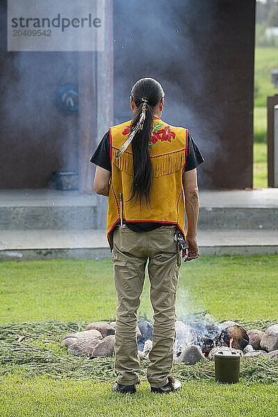 Person standing in front of a fire during a drum dance in Fort Simpson  NWT.