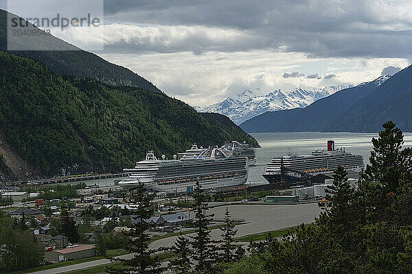 Cruise ships are seen docked at the Port of Skagway in southern Alaska. Large mountains adorn the landscape and make a scene that is magnificent to behold.