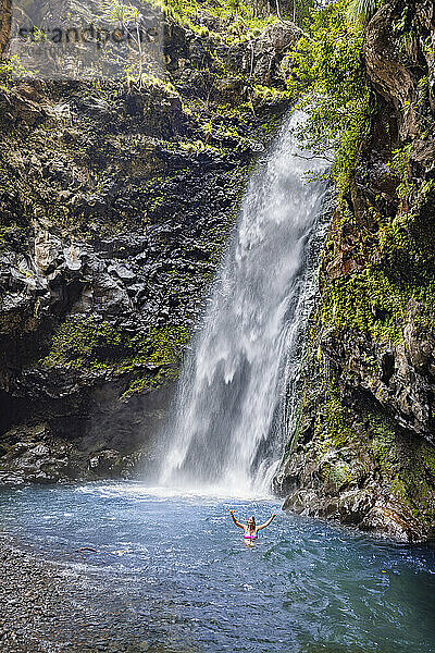 A young lady (MR) cools off in a pool below one of the many roadside waterfalls on the road to Hana  Kipahulu  Maui  Hawaii.