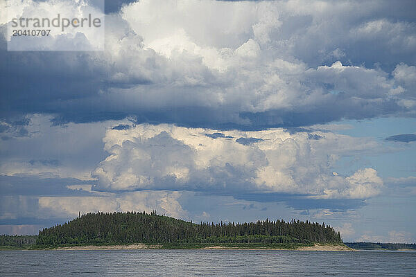 Summer clouds form over an island in the middle of the Mackenzie River  Northwest Territories.