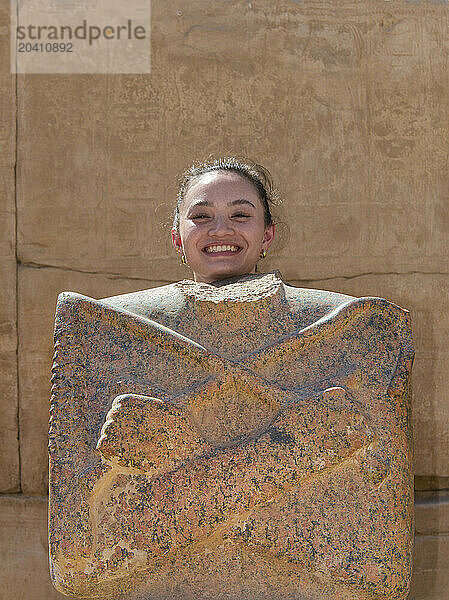 Gan 15483 Young girl posing as ancient Egyptian god with headless statue  Karnak temple  Luxor Egypt