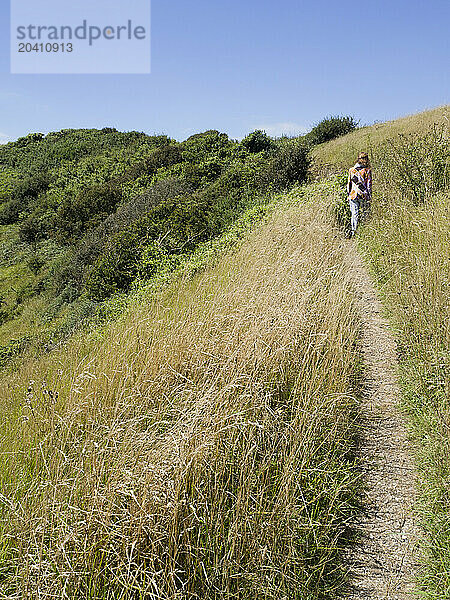 Woman walking on a coast path in the south of England near Beachy Head  Eastbourne  East Sussex  UK © Renzo Frontoni