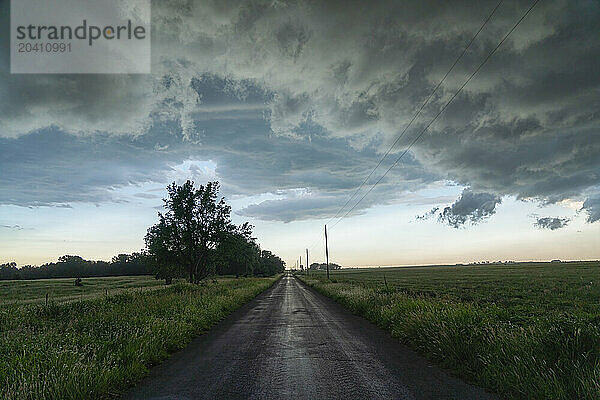 Road leading into the distance as a thunderstorm passes by overhead.