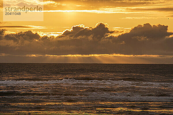 Beautiful sunset with fingers of God extending down from behind the clouds over the Pacific Ocean from the beach at Cape Disappointment State Park near the mouth of the Columbia River  Washington State.