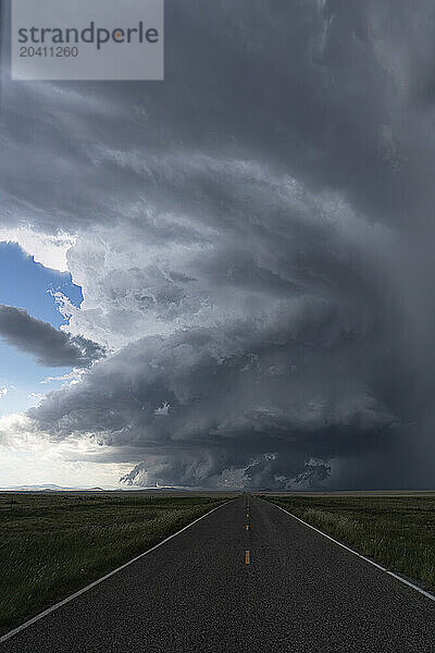 Dramatic clouds associated with a very strong supercell thunderstorm in New Mexico. Road leading into the distance directly into the storm.