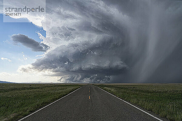 Dramatic clouds associated with a very strong supercell thunderstorm in New Mexico. Road leading into the distance directly into the storm.