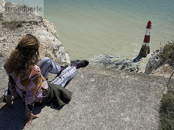 Woman sitting and looking at Beachy Head Lighthouse and the sea from a vantage point  Beachy Head  East Sussex  UK © Renzo Frontoni