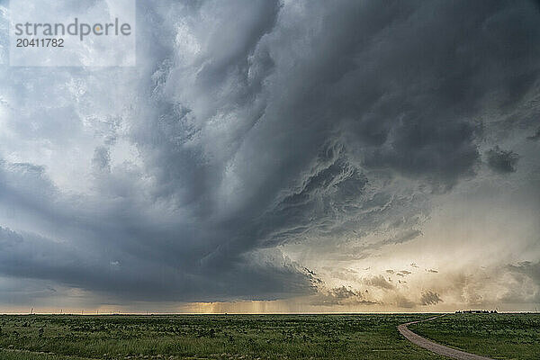 Strong thunderstom over the southern plains of Colorado. Dramatic clouds are present with a road leading to a distant farm.