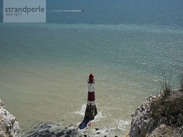 Beachy Head Lighthouse seen from the coast path above with glittering sea and a speedboat on a sunny day  East Sussex  UK © Renzo Frontoni