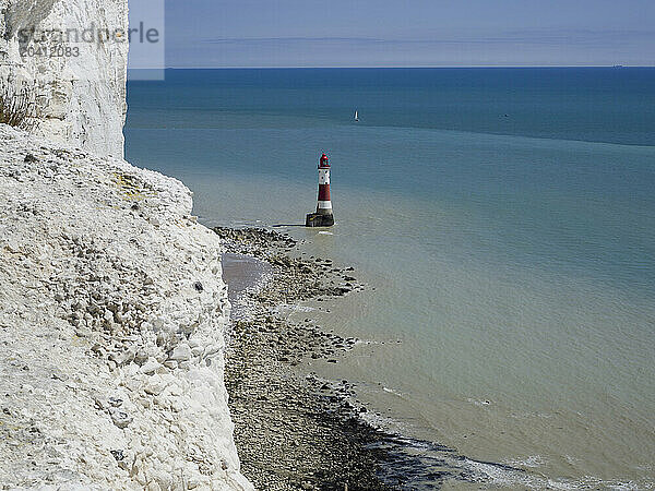 Beachy Head Lighthouse seen from the coast path above with white chalk cliffs and a sailing boat in the distance  East Sussex  UK © Renzo Frontoni