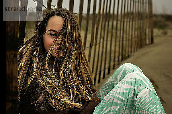 Beautiful young girl looking at camera on windy beach