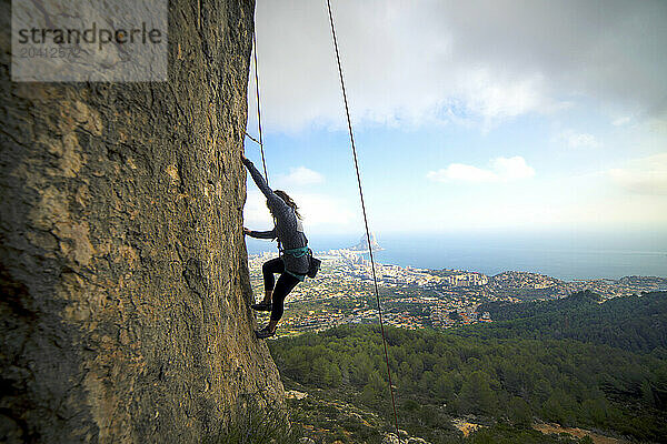 Woman climbing rocky cliff at Olta