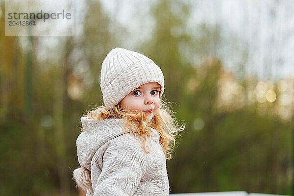 Portrait of a smiling girl in a hat against a forest background