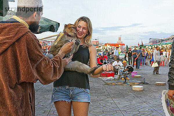 Tourist Holding A Trained Barbary Monkey In Jemaa El Fna Square