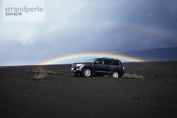 Four wheel dive car in the ash fall from volcano EyjafjallajÃ¶kull  with a perfect rainbow in the background