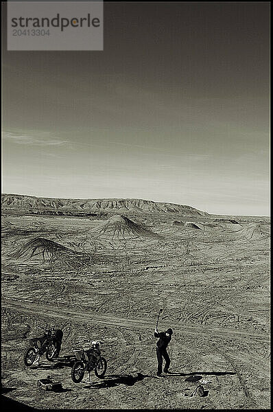 A young man hits golf balls while taking a break from motocross riding during a trip to the Painted Desert near Cameron  AZ.