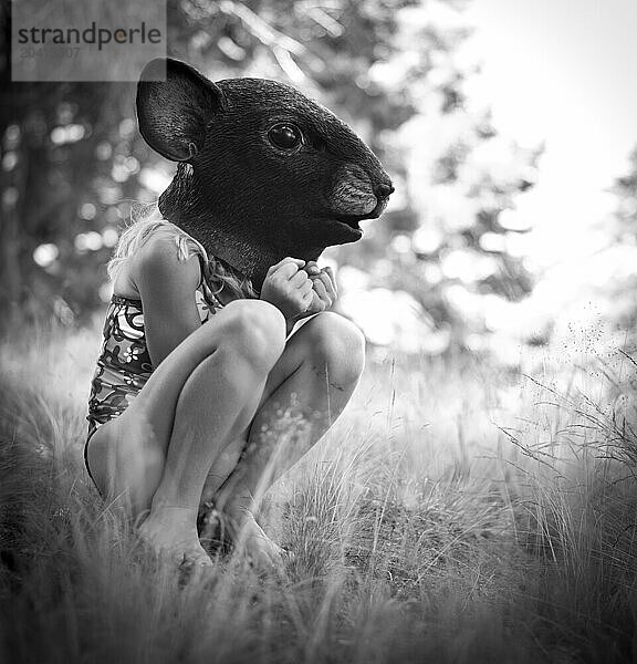 girl in a mouse mask sits in the grass